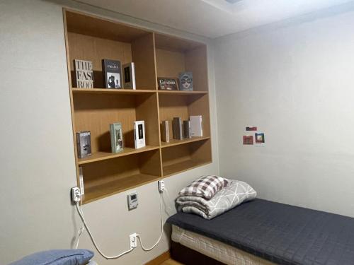 a bedroom with a bed and a book shelf at Halla guest house in Jeju
