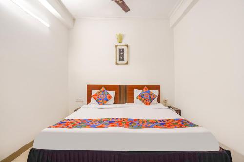 1 dormitorio con 1 cama grande con colcha blanca en FabHotel Sai Residency, en Agra