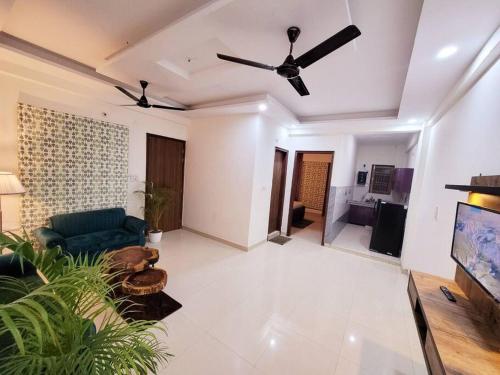een woonkamer met een bank en een plafondventilator bij Utopia' Entire 1BHK Flat In Noida 63A in Noida