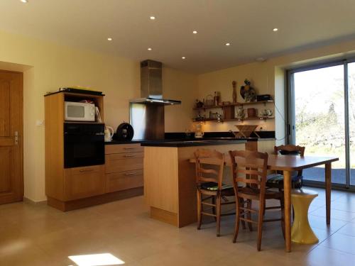 a large kitchen with a table and a microwave at Gîte de France Gîte de duroux 3 épis - Gîte de France 6 personnes MAE-9134 in Estivals