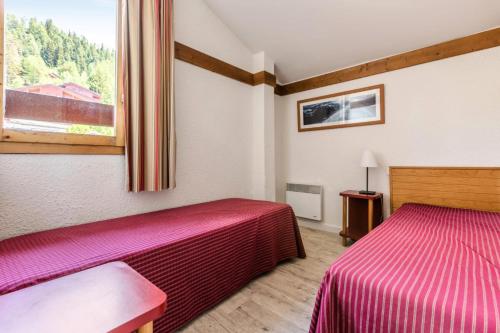 a hotel room with two beds and a window at Résidence Plagne Lauze - maeva Home - Appartement 4 pièces 8 personnes Sele 93 in Mâcot La Plagne
