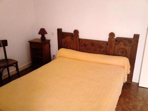 1 dormitorio con cama de madera y manta amarilla en Gîte de France à Couffy-sur-Sarsonne 2 épis - Gîte de France 7 personnes 124, 