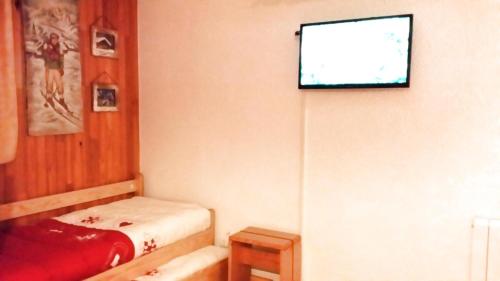 a room with a bed and a tv on the wall at Studio 4 pers pied des pistes 80267 in Lanslevillard