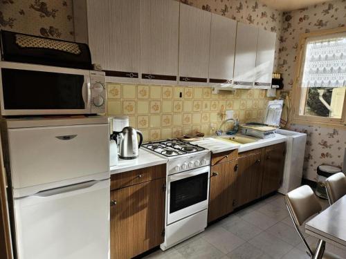 une cuisine avec une cuisinière blanche et un micro-ondes dans l'établissement Gîte de France à Eygurande 2 épis - Gîte de France 4 personnes MAE-9164, à Eygurande