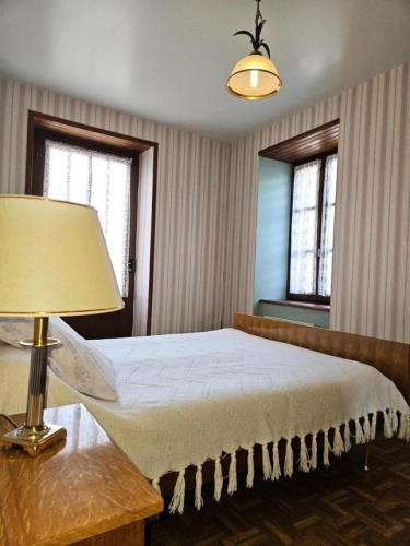 - une chambre avec un lit, une lampe et deux fenêtres dans l'établissement Gîte de France à Eygurande 2 épis - Gîte de France 4 personnes MAE-9164, à Eygurande