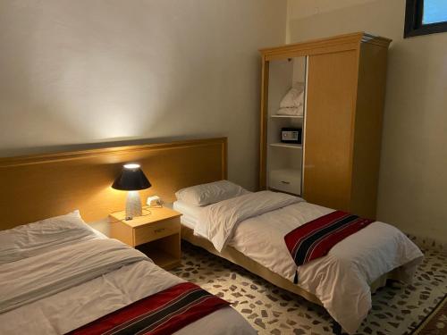 a hotel room with two beds and a night stand at Madaba Mesha Stele Bedoiun Apartments in Madaba