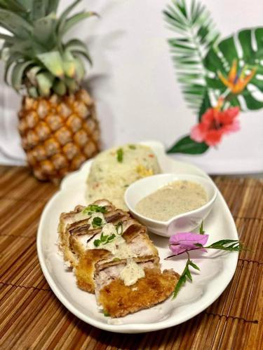 a plate of food with a sandwich and a bowl of dip at Pension Hibiscus Taha'a in Vaitoare