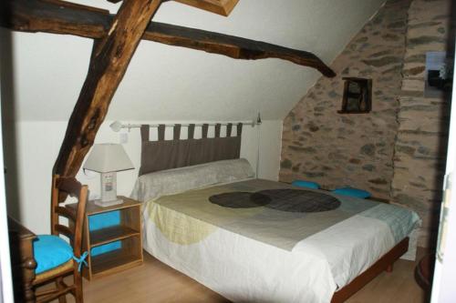 1 dormitorio con cama y pared de piedra en Gîte de France Pierrelise 3 épis - Gîte de France 8 personnes 194, en Espartignac