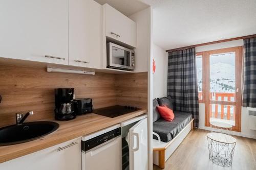 une petite cuisine avec un évier et un micro-ondes dans l'établissement Résidence Les Constellations - maeva Home - 2 Pièces 5 personnes Sélection MAE-7324, à La Plagne Tarentaise