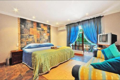 1 dormitorio con 1 cama, TV y sofá en Amakoekoe Guest Lodge & Conference Venue, en Johannesburgo