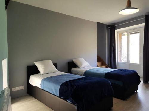 una camera con due letti con lenzuola blu e bianche di Gîte de France à Alleyrat 3 épis - Gîte de France 4 personnes 324 ad Alleyrat
