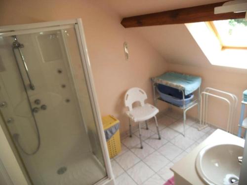 uma casa de banho com um chuveiro, um lavatório e uma cadeira. em Gîte de France à Sarroux - St Julien 3 épis - Gîte de France 6 personnes 414 em Sarroux