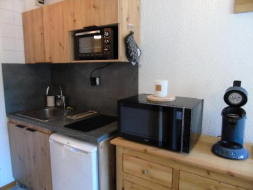 a small kitchen with a microwave and a sink at Résidence Thabor - Studio pour 3 Personnes 704 in Modane