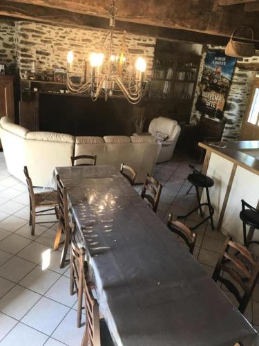 a dining room with a table and chairs and a couch at Gîte de France "les volets bleus" 3 épis - Gîte de France 12 personnes MAE-9484 in Espartignac