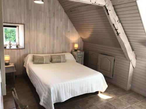 a bedroom with a white bed in a wooden wall at Gîte de France "les volets bleus" épis - Gîte de France 484 in Espartignac