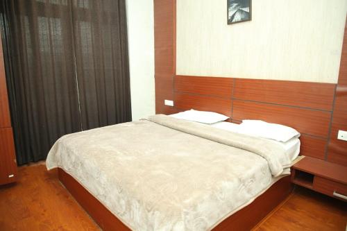 een slaapkamer met een groot bed met een houten hoofdeinde bij TAT HOLIDAYS Armaan Groups in Ooty