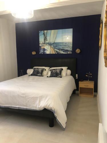 een slaapkamer met een groot bed en een schilderij aan de muur bij Agréable appartement Chez Mamé Jeanne au Grau du Roi in Le Grau-du-Roi
