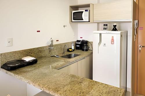a kitchen with a sink and a refrigerator at Studio Top Life: Garagem | Wifi | Ar-condicionado NA1002 in Juiz de Fora