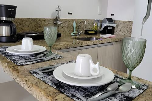 a kitchen counter with two white plates and spoons at Studio Top Life: Garagem | Wifi | Ar-condicionado NA1002 in Juiz de Fora