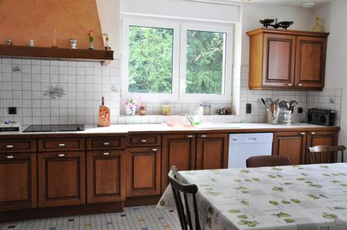eine Küche mit Holzschränken, einem Tisch und einem Fenster in der Unterkunft Gîte de France à Soudeilles épis - Gîte de France 574 
