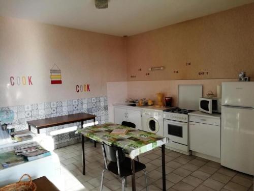 une cuisine avec un réfrigérateur et une table à l'intérieur dans l'établissement Gîte de France Gîte communal 2 épis - Gîte de France 3 personnes MAE-9604, à Saint-Hilaire-les-Courbes