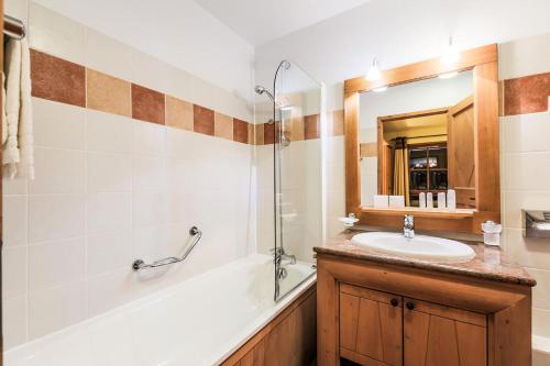 une salle de bain avec un lavabo, une baignoire et un miroir dans l'établissement Résidence Les Arcs 1950 Le Village - maeva Home - Appartement 3 pièces 6 personnes Selection MAE-1756, à Bourg-Saint-Maurice
