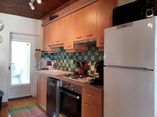une cuisine avec des armoires en bois et un réfrigérateur blanc dans l'établissement Gîte de France Les hortensias 3 épis - Gîte de France 2 personnes MAE-9614, à Albussac
