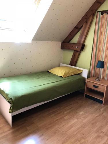 - une chambre mansardée avec un lit vert dans l'établissement Gîte de France Les pouges 3 épis - Gîte de France 6 personnes MAE-9594, à Chameyrat