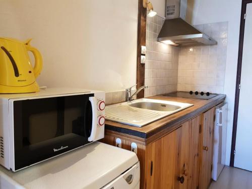 une petite cuisine avec un micro-ondes et un évier dans l'établissement Résidence Les Arolles - Apartement 2 pièces 6 personnes à Arc 1600 en centre station et proche des pistes MAE-1701, à Arc 1600