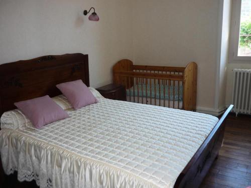 1 dormitorio con cama con almohadas rosas y cuna en Gîte de France à Vars-sur-Roseix 3 épis - Gîte de France 5 personnes 624, 