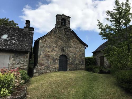 an old stone building with a door and a tower at Gîte de France Le rouzeyrol 3 épis - Gîte de France 12 personnes MAE-9674 in Charbonniers