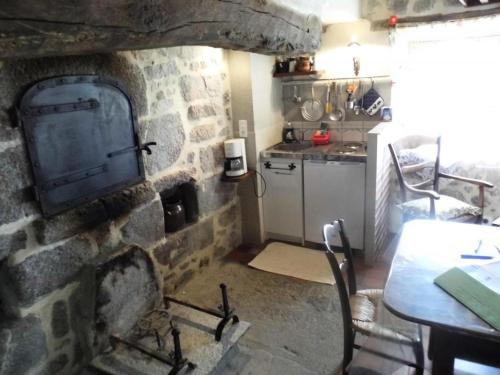 uma cozinha com uma parede de pedra com uma mesa e um fogão em Gîte de France à Chaveroche 2 épis - Gîte de France 2 personnes 664 