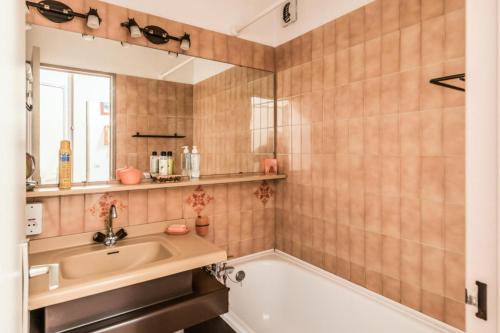 une salle de bain avec un lavabo, une baignoire et un miroir dans l'établissement L'Aiguille - maeva Home - Appartement 2 pièces 5 personnes Confort MAE-2592, à Chamonix-Mont-Blanc