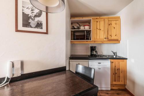 une petite cuisine avec une table et un réfrigérateur dans l'établissement Résidence Quartier Falaise - maeva Home - Appartement 2 pièces 4 personnes Sélection MAE-2593, à Avoriaz