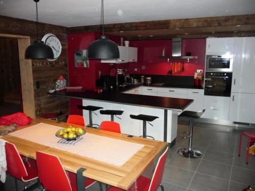 ヴァルモレルにあるChalet belle vue montagne proche Valmorel 86009の赤い壁のキッチン(木製テーブル付)