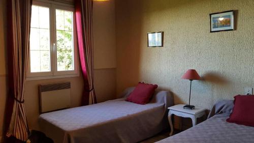 a bedroom with two beds with red pillows and a window at Gîte de France à Lagleygeolle 3 épis - Gîte de France 4 personnes MAE-9734 in Lagleygeolle