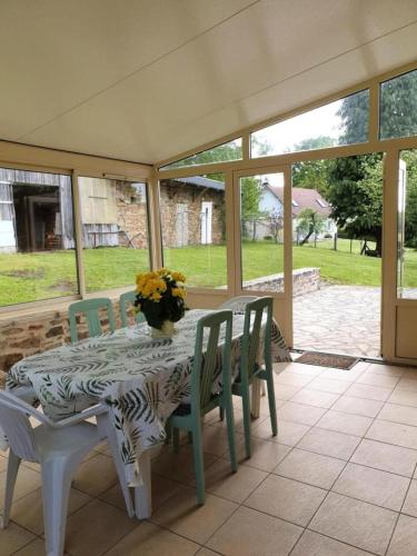 - une table avec des chaises et un vase de fleurs sur la terrasse dans l'établissement Gîte de France Gîte de lachaud 3 épis - Gîte de France 4 personnes MAE-9774, à Albussac