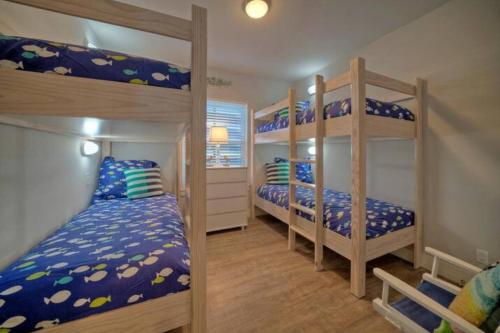 a bedroom with two bunk beds with blue sheets at Rock N Reel by AvantStay Old Town Location in Port Aransas
