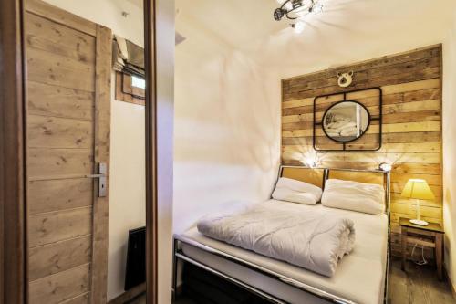 a bed in a room with a wooden wall at Résidence Les Ravines - maeva Home - 2 pièces 4 personnes Sélection MAE-3913 in Les Allues