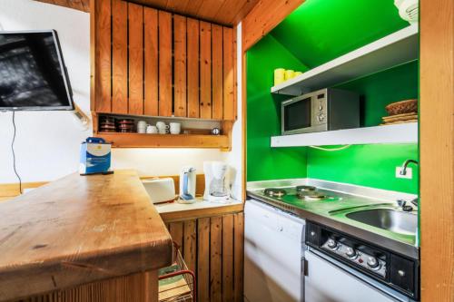 - une cuisine verte avec évier et cuisinière dans l'établissement Résidences quartier Charmettoger - maeva Home - Grand studio duplex 5 personnes Budget MAE-4995, à Arc 1800