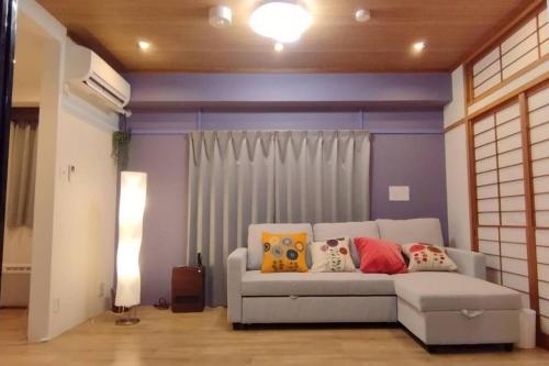 a living room with a white couch with pillows at Nagoya Apartment Oosu in Minami-sotoborichō