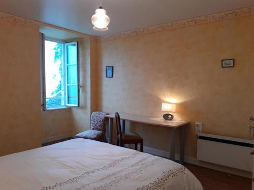 Saint-RobertにあるGîte de France Le colibri 2 épis - Gîte de France 6 personnes MAE-9894のベッドと机と窓のある寝室