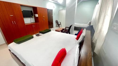 a bedroom with a large white bed with red pillows at Brundavan in Hyderabad