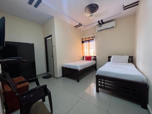 Cette chambre comprend 2 lits et une télévision. dans l'établissement Brundavan, à Hyderabad