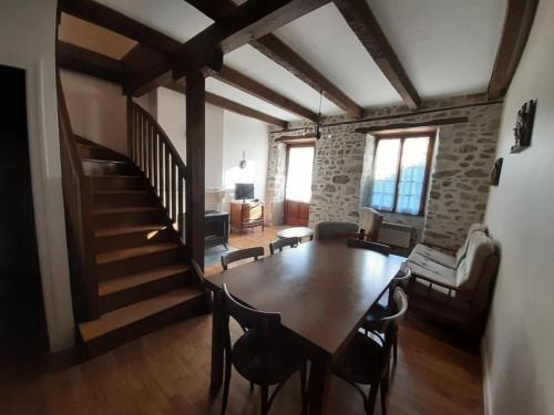 a living room with a wooden table and a staircase at Gîte de France à Lamazière-Haute 2 épis - Gîte de France 5 personnes MAE-9934 in Lamazière-Haute