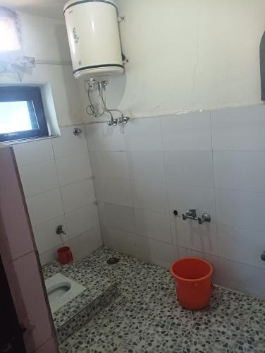 a bathroom with a toilet and a window and a bucket at Malik guest house in Wāngom