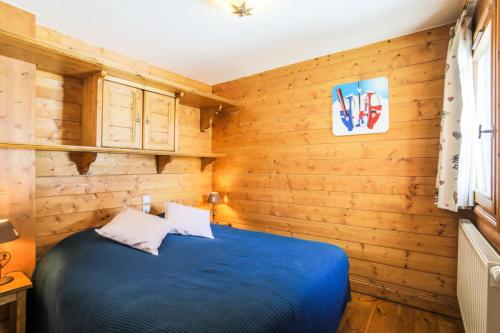 レ・メニュアールにあるRésidence Les Alpages de Reberty - maeva Home - Appartement 3 pièces 6 pers 26の木製の壁と青いベッドが備わるベッドルーム1室が備わります。