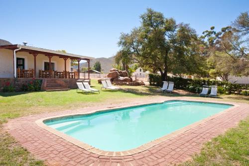 a swimming pool in a yard with chairs and a house at Red Stone Hills in Buffelskloof