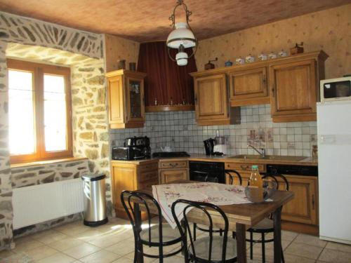 une cuisine avec une table et des chaises et une cuisine avec des placards en bois dans l'établissement Gîte de France Gite de la genette 3 épis - Gîte de France 8 personnes MAE-0024, à Beyssenac