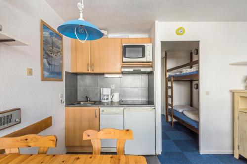 Il comprend une petite cuisine avec 2 chaises et des lits superposés. dans l'établissement Résidence Les Alpages - maeva Home - Studio 1 pièce 4 personnes Sélection MAE-9982, à Morzine